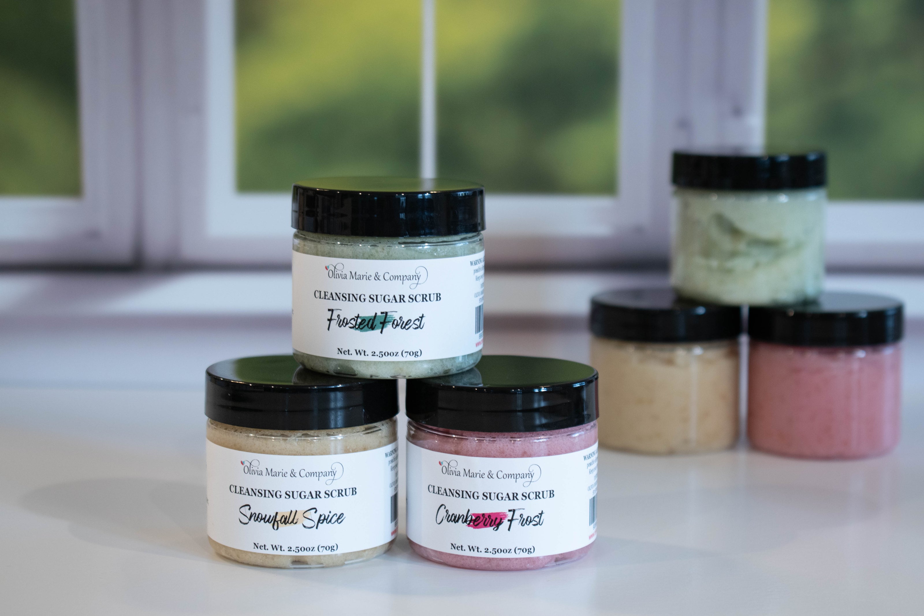 Jars of cleansing sugar scrub with visible labels on a surface.