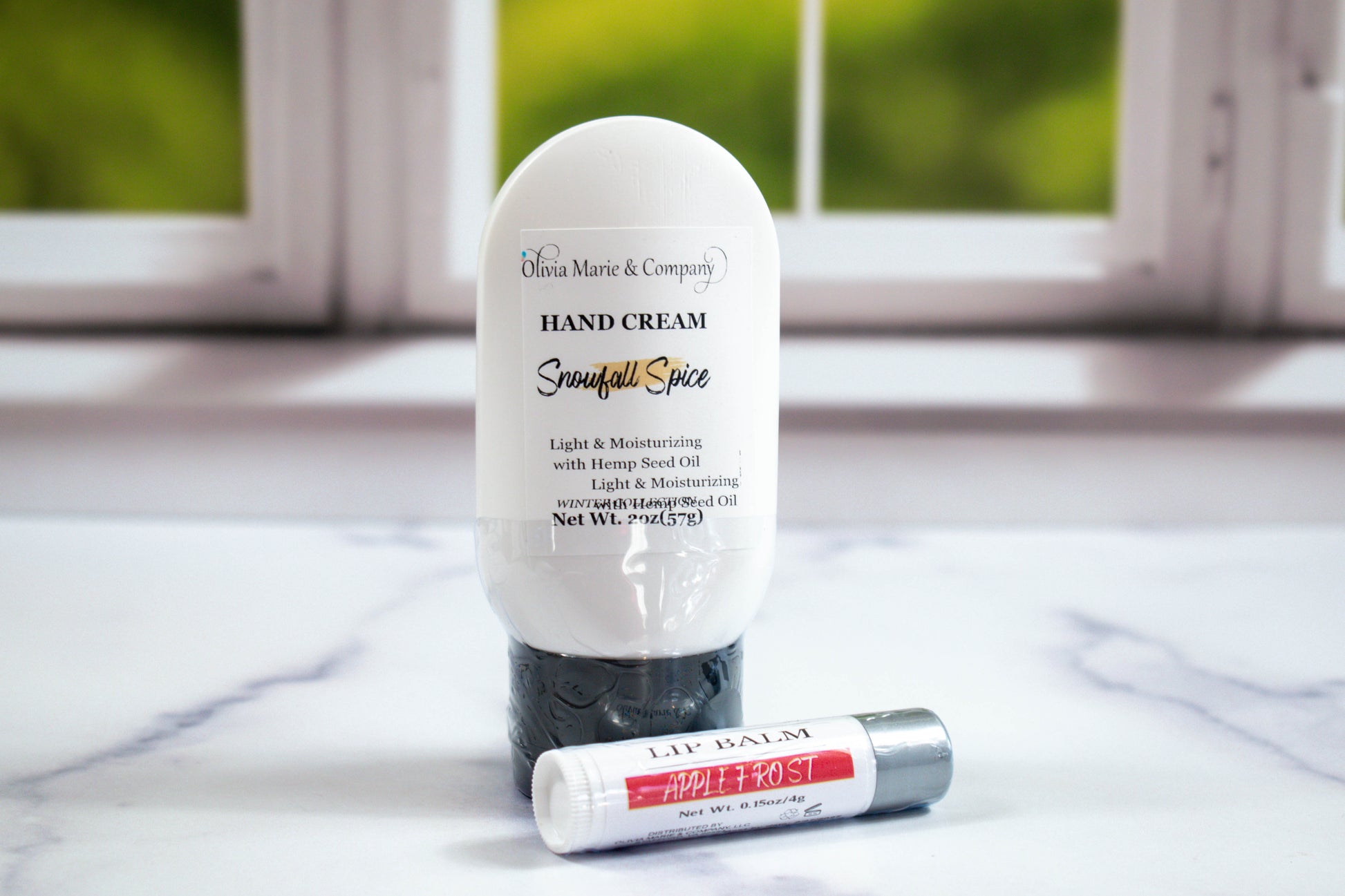 Hand cream and lip balm on a marble surface with a blurred window background