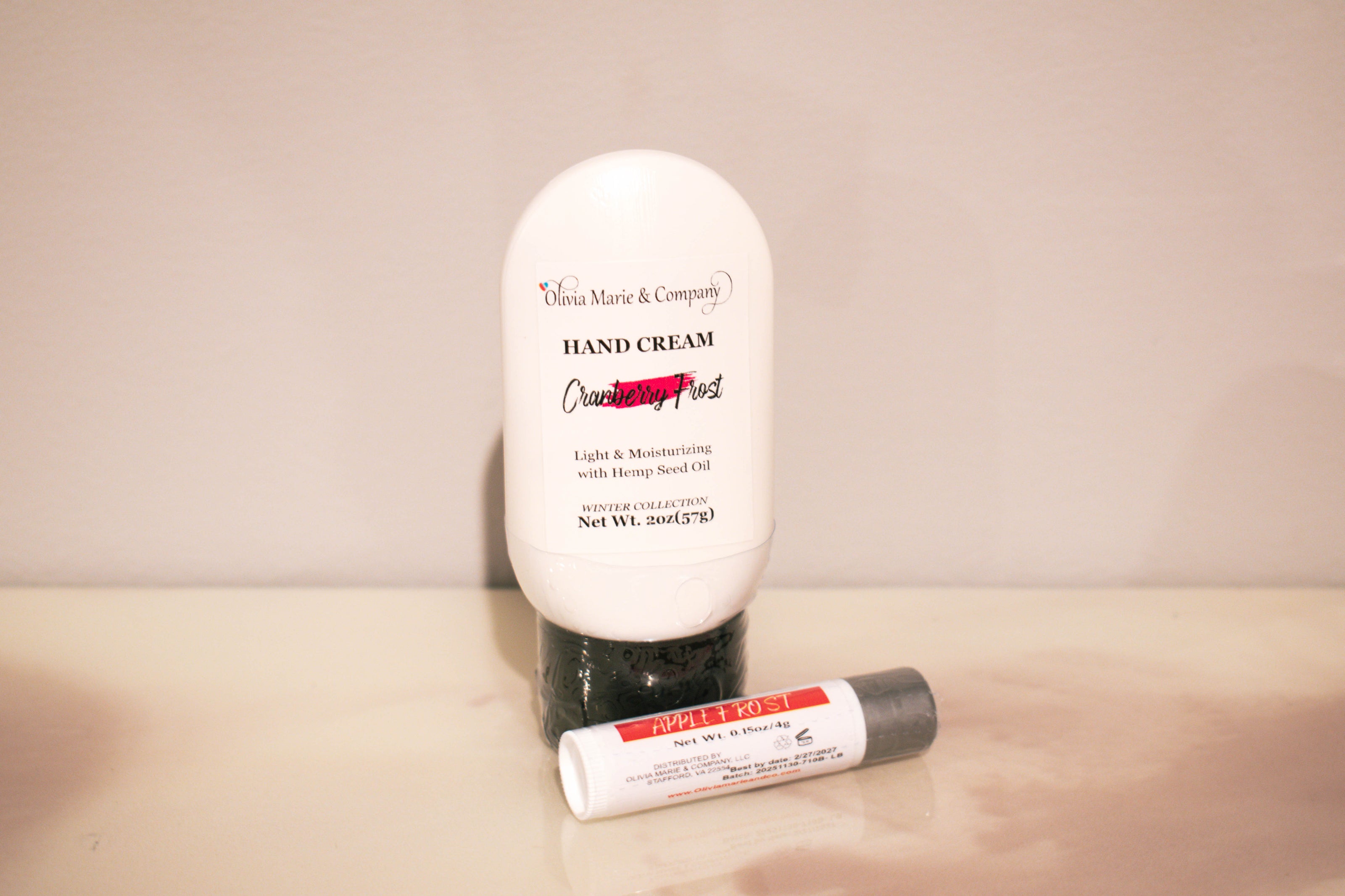 Hand cream and lip balm set on a beige surface with a neutral background